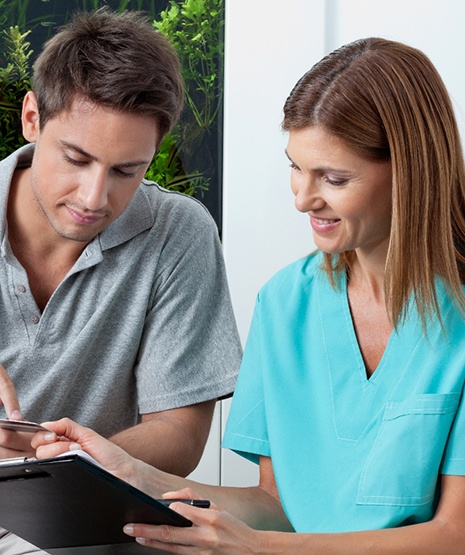 Young man showing payment card information to medical professional holding clipboard